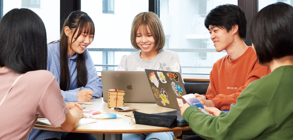 東洋美術学校グラフィックデザイン科の学生と高度コミュニケーションデザイン専攻の学生がデザインについて話し合っている様子。