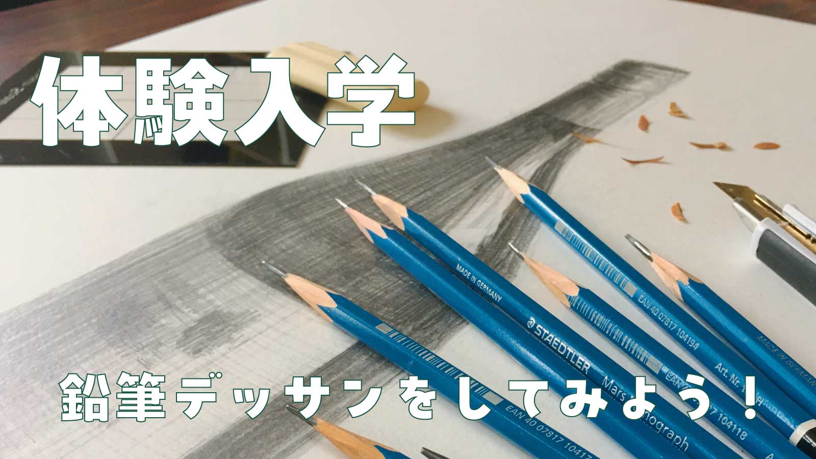 ワインボトルのデッサン作品の上に、鉛筆やカッターナイフなどの道具が並んでいる写真。東美の体験入学　鉛筆デッサンをしてみようのテキストが入っている。