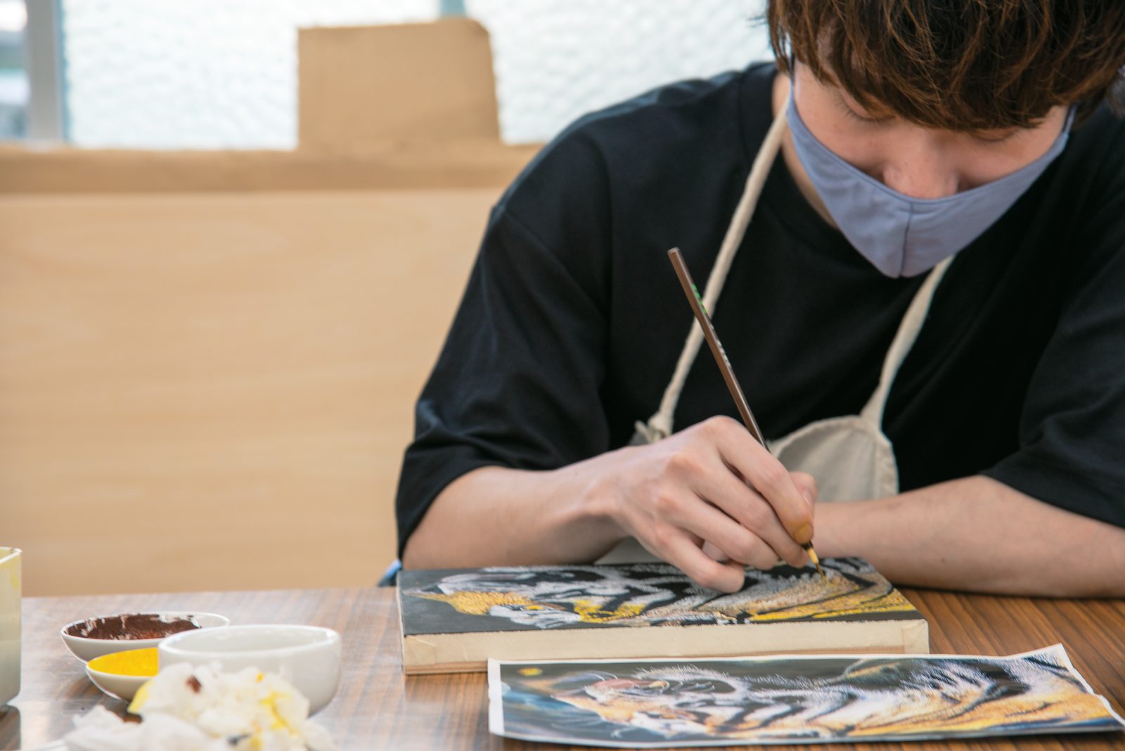 額装された作品に筆を入れる修復作業